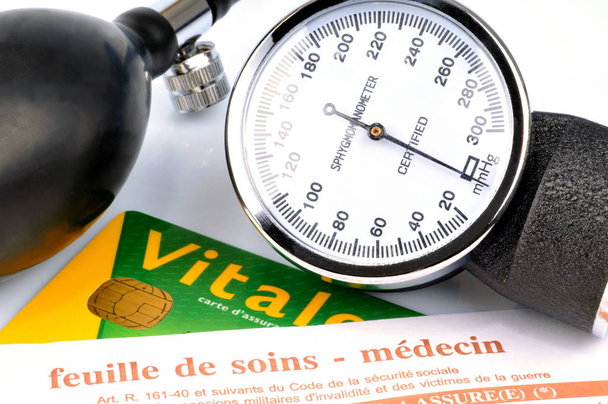französisches Behandlungsblatt mit Vitalkarte und Blutdruckmessgerät in Großaufnahme - Foto, Bild