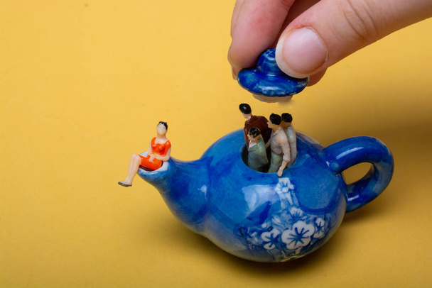 Группа миниатюрных людей фигуры, стоящие в чайнике
 - Фото, изображение