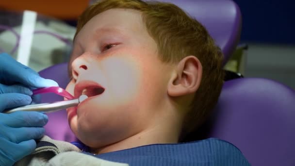 Scared red-haired boy crying at reception at dentist in dental chair. Pediatric dentistry - Footage, Video