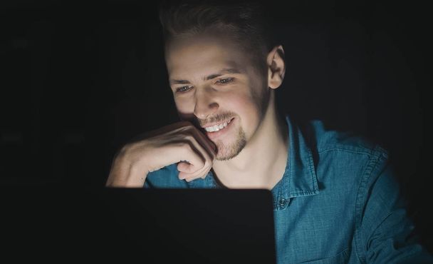 Smiling man using laptop at night - Φωτογραφία, εικόνα