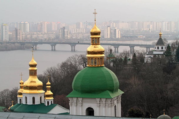 Complejo de templos ortodoxos Lavra en el fondo de los edificios y puentes de la ciudad moderna de Kiev
 - Foto, imagen