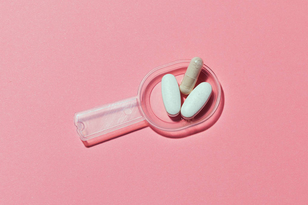 Műanyag mérőkanál orvosi tabletták rózsaszín háttér. - Fotó, kép
