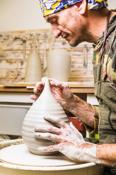 Porträt eines Töpfers, der Tonschalen oder Vasenkeramik auf der Töpferscheibe herstellt. Töpferkunst und handwerkliche Modellierung.  - Foto, Bild