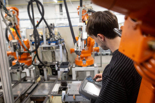 Hombre joven programando robot automático industrial en la industria automotriz
 - Foto, Imagen