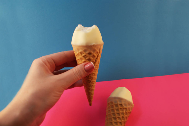 La mano femminile tiene il gelato in un cono su uno sfondo colorato
. - Foto, immagini