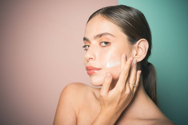 Sexy healthy woman applying cream or lotion with moisturizer to skin face. Perfect pure skin. Healthy and wellness concept. Natural beauty and no make up concept. - Foto, imagen