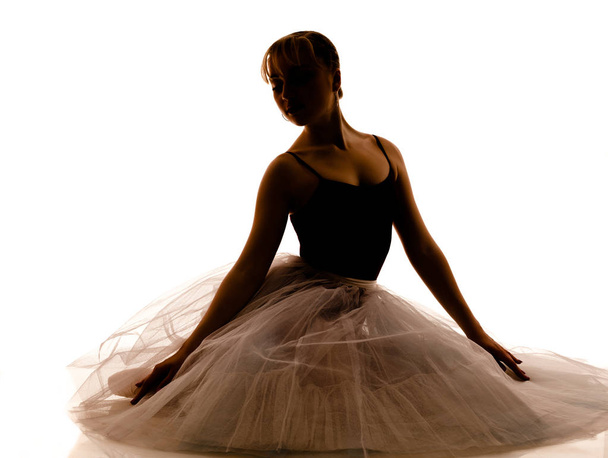 Silhouette of young beautiful ballerina in white tutu and pointe shoes doing dancing pose - Foto, afbeelding