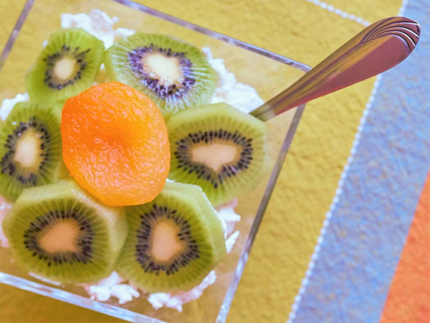 Десерт с творогом, киви и сушеным абрикосом в стеклянной миске, вид сверху
. - Фото, изображение