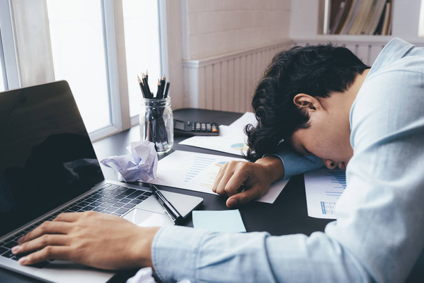 Un jeune homme d'affaires qui travaille dur et dort à son bureau
.   - Photo, image
