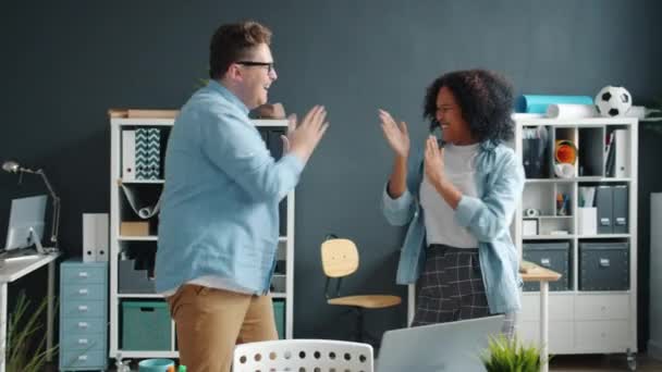 Afro-American lady and Caucasian man dancing clapping hands having fun in office - Filmmaterial, Video