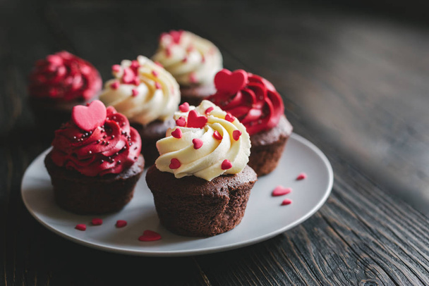 赤い色のバレンタインカップケーキ、プレート上で提供し、甘い心で飾られています.  - 写真・画像