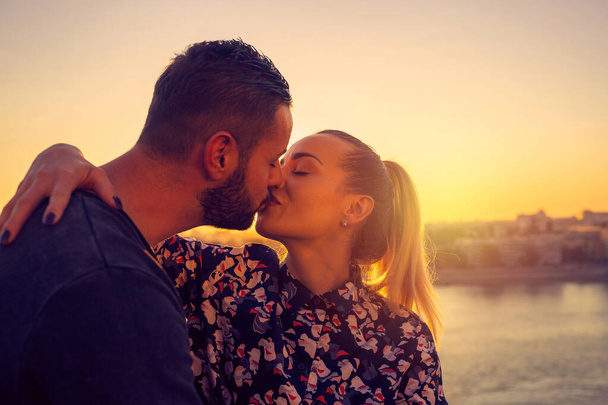 Άντρας και γυναίκα ερωτευμένοι φιλιούνται στο ηλιοβασίλεμα - Φωτογραφία, εικόνα
