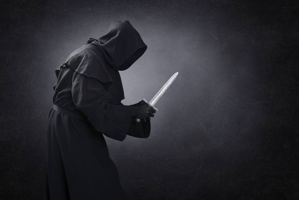Человек в капюшоне с кинжалом в темноте
 - Фото, изображение