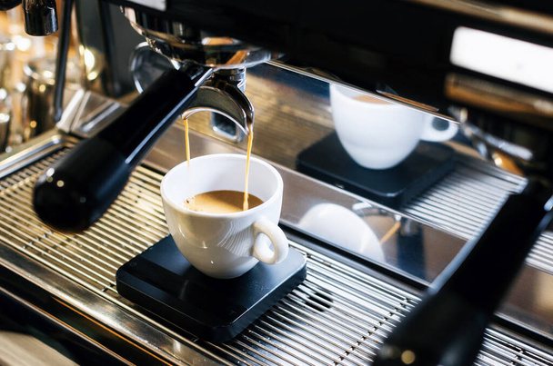 Эспрессо-машина наливает кофе в белую чашку
 - Фото, изображение