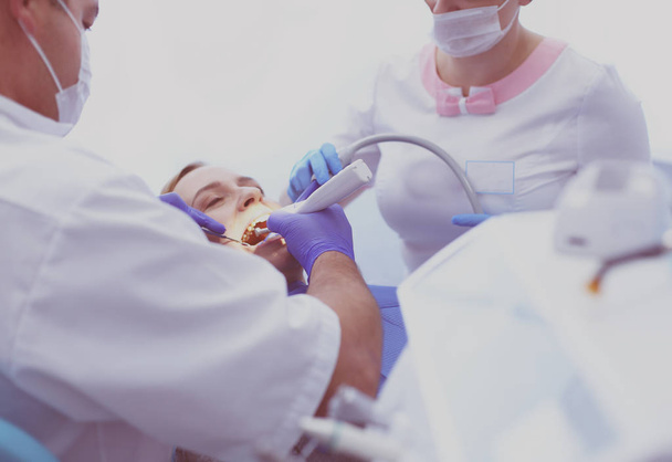 Immagine di una giovane donna con dentista sopra di lei prima di controllare la cavità orale - Foto, immagini
