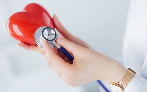 Ein Arzt mit Stethoskop untersucht rotes Herz, isoliert auf weißem Hintergrund - Foto, Bild