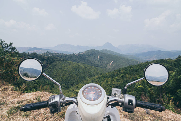 Manillar de moto con montañas laosianas sobre fondo
 - Foto, imagen