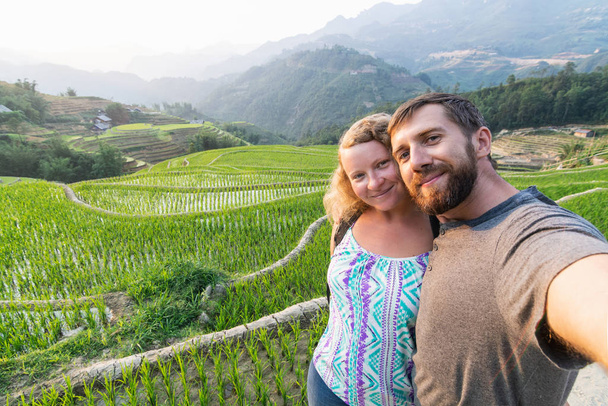 Young Caucasian couple making selfie at rice terraces of Sapa in Lao Cai region of Vietnam - Photo, Image