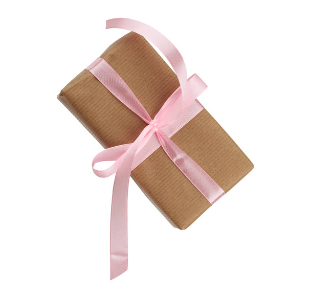 prostokątne pudełko owinięte w brązowy papier i związane różową kokardą - Zdjęcie, obraz
