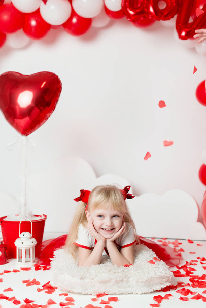 Valentin nap - portré egy aranyos kislány egy díszített stúdióban. Gyönyörű kislány Cupidónak öltözve. - Fotó, kép