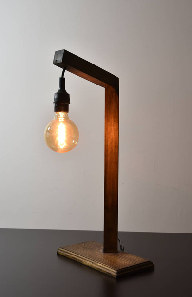 Handmade wooden lamp on gray background with retro edison bulb - Photo, Image
