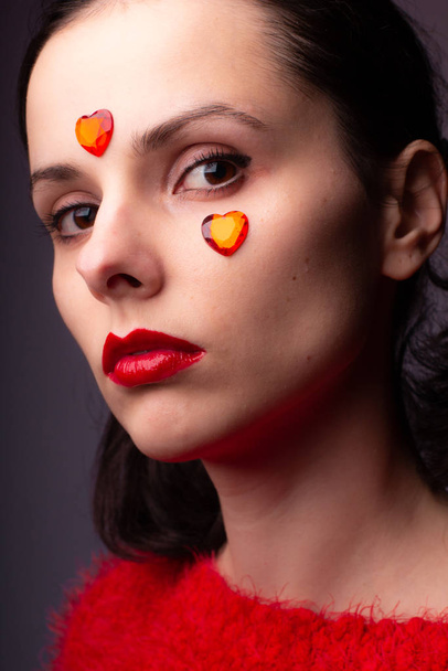 girl in a red sweater with red lips and a red heart on her face - Фото, зображення