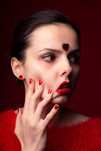 beautiful girl in red with a heart on her forehead, emotional portrait - Photo, Image