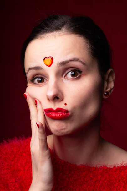 beautiful girl in red with a heart on her forehead, emotional portrait - Foto, Bild