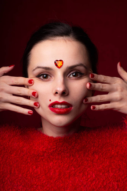 beautiful girl in red with a heart on her forehead, emotional portrait - Foto, Imagen