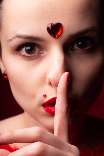 beautiful girl in red with a heart on her forehead, emotional portrait - 写真・画像
