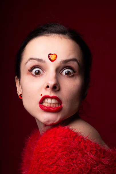 beautiful girl in red with a heart on her forehead, emotional portrait - Foto, afbeelding