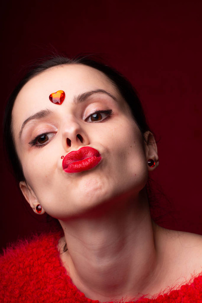 beautiful girl in red with a heart on her forehead, emotional portrait - Фото, зображення