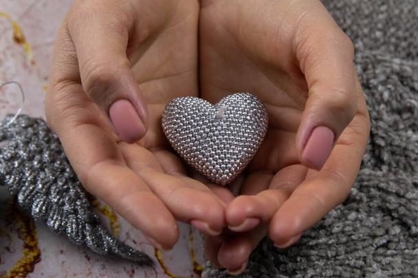 Un fondo de San Valentín. Las manos hermosas de las mujeres con una delicada manicura mate hacen una hermosa vela gris
 - Foto, Imagen
