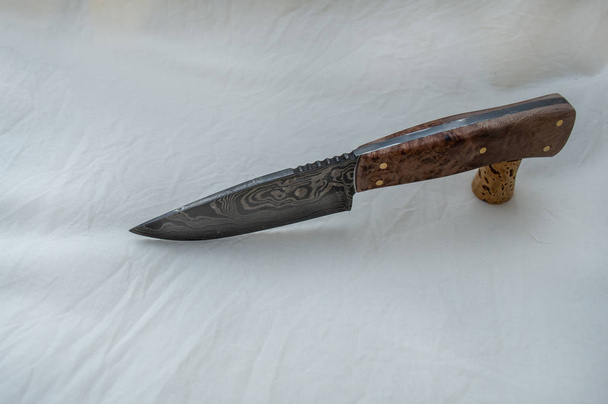 A pretty handle and a pretty damascus blade makes this a knife fit for the hunter or the collector and a great gift item. Displayed on fabric there is plenty of copy space. Bokeh effect. - Photo, Image