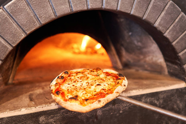 Cocinado sabrosa pizza margherita en horno de leña tradicional en el restaurante Nápoles, Italia. pizza napolitana original. Carbón rojo caliente
. - Foto, imagen