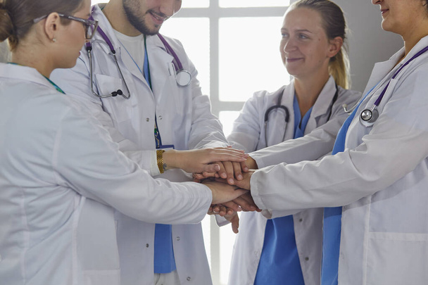 Een team van medici die elkaars handen bij elkaar houden, binnen, boven het zicht. Eenheidsconcept - Foto, afbeelding