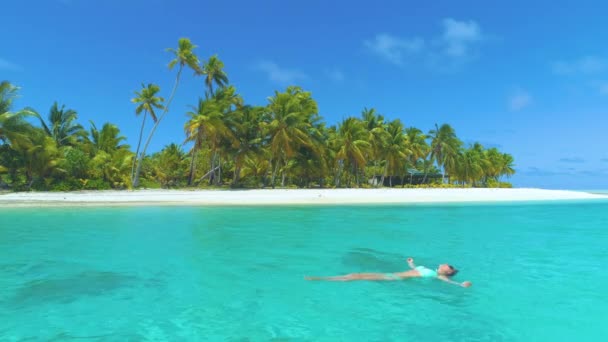 DRONE: Vrouwelijke reiziger ontspannen door te zweven op het oppervlak van turquoise oceaan. - Video