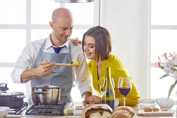 Souriant jeune couple cuisine des aliments dans la cuisine - Photo, image