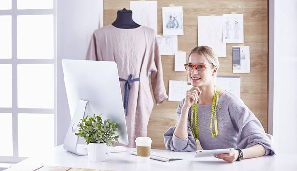 Attractive fashion designer working in office, leaning on desk, drawing - Foto, afbeelding
