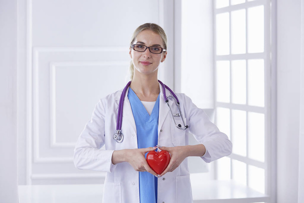 Γιατρός με στηθοσκόπιο που κρατά την καρδιά, απομονωμένος σε λευκό φόντο - Φωτογραφία, εικόνα
