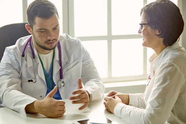 Young doctor talking to a patient in the office - Photo, Image
