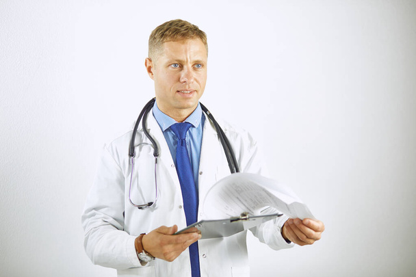 Молодой уверенный доктор в белом халате со стетоскопом - Фото, изображение