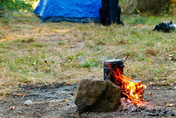 Főzés a tábortűz kemping. Sátor és hátizsák a háttérben - Fotó, kép