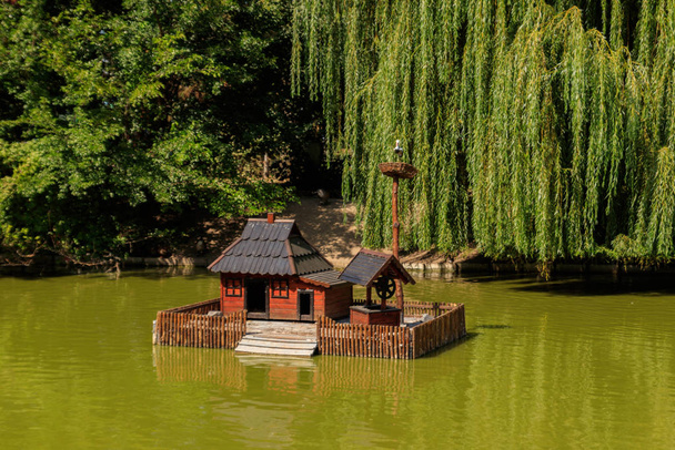 Деревянный дом для водных птиц и черепах на озере в городском парке
 - Фото, изображение