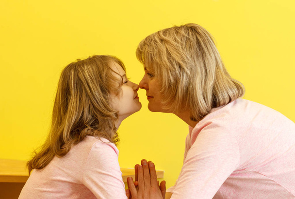 Mom and daughter in the same pink T-shirts face to face touched each other. - Photo, Image