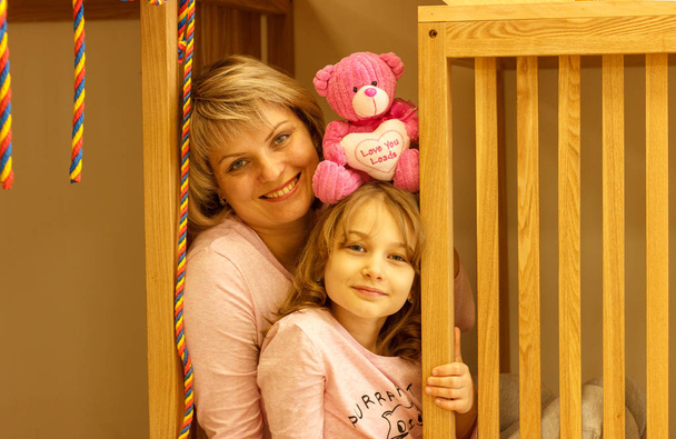Mãe e filha juntas em uma sala de jogos infantil com um ursinho de pelúcia
. - Foto, Imagem
