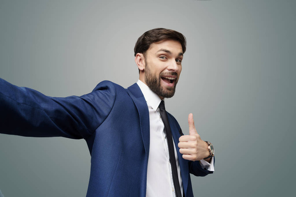 wide angle selfie shot of young business man going thumb up on grey background - Φωτογραφία, εικόνα