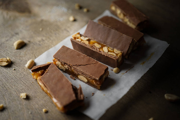 Homemade snickers bars. Peanuts in caramel covered with milk chocolate. side view - 写真・画像