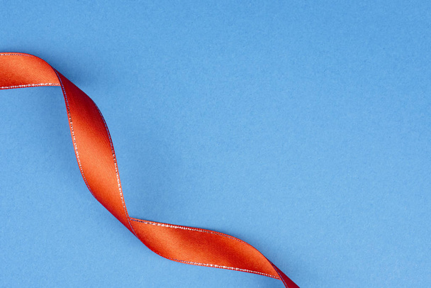 Red wriggling ribbon with silver stitching on a blue background. - Foto, immagini