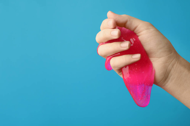 Woman playing with pink slime on light blue background, closeup. - Foto, immagini